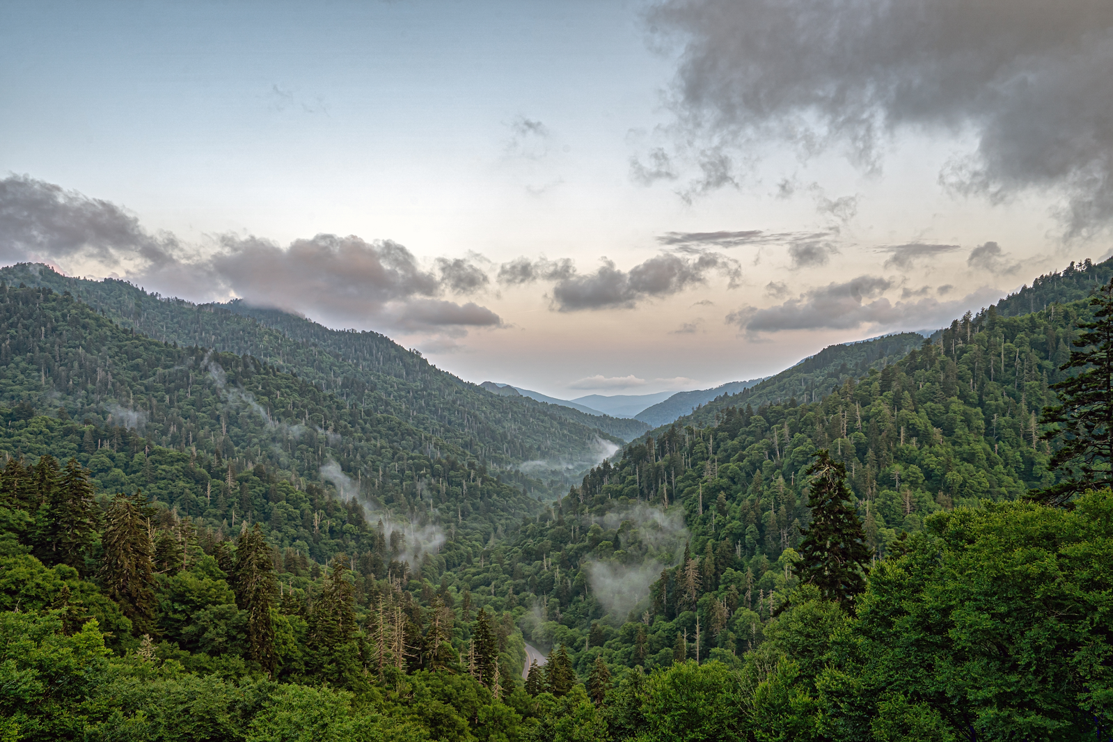 hiker sitting on cliff looking out at Smoky Mountain landscape